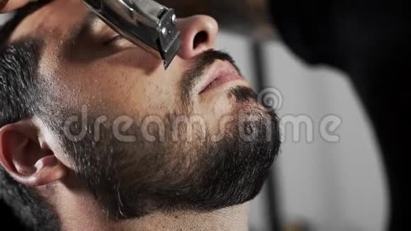 理发师在理发店用修剪机和梳子剪顾客的胡子男士理发和刮胡子视频的预览图