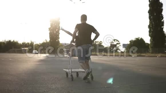 一对年轻夫妇出去玩的背面镜头骑在购物车上太阳照耀着背景视频的预览图
