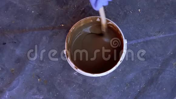 油漆和修理桶里的油漆用棍子搅拌视频的预览图