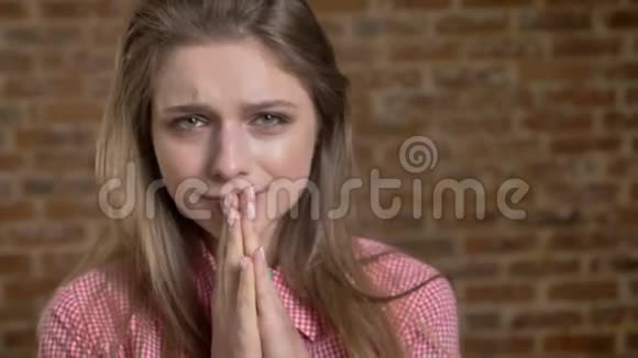 年轻有感情的女孩正在哭在镜头前看着砖背景视频的预览图