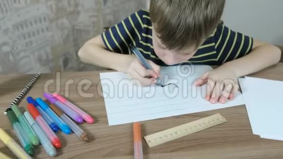 七岁的男孩正在用坐在桌子旁的条纹纸画他的颜料视频的预览图