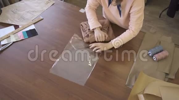 年轻的女裁缝正在整理衣服站在缝纫室的桌子旁职业的是在木桌上工作视频的预览图