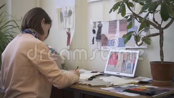 女时装设计师正在画画坐在缝纫车间的桌子旁女设计师正在用铅笔做创意工作视频的预览图