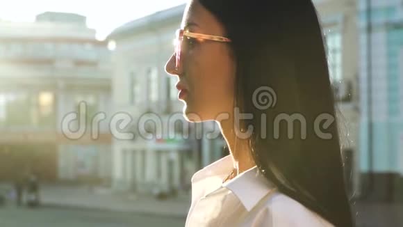在阳光下戴着太阳镜的漂亮黑发女郎视频的预览图