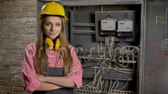 年轻自信的女建筑工人站在电线和电表附近交叉双臂看着摄像机建筑视频的预览图