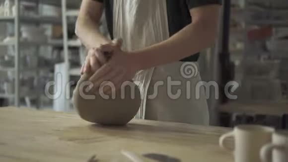在陶器车间穿围裙的工匠在工作台上揉捏了很多粘土视频的预览图