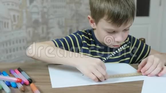 7岁的男孩穿着条纹t恤用铅笔和尺子在纸上画均匀的线条视频的预览图