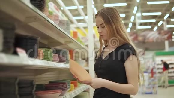 单身女人在超市里拿盘子从货架上拿出来视频的预览图