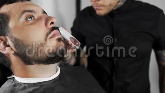 理发师在理发店用剪子剪了顾客胡子男人在理发剪了胡子视频的预览图