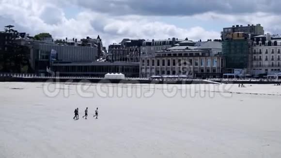 白色海滩游客在城市的背景下行动男人在城市背景和多云的天空中沿着白色的海滩奔跑视频的预览图