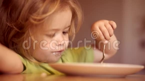 可爱的孩子在家吃早餐可爱的小笑男娃娃的肖像金发从盘子里吃视频的预览图