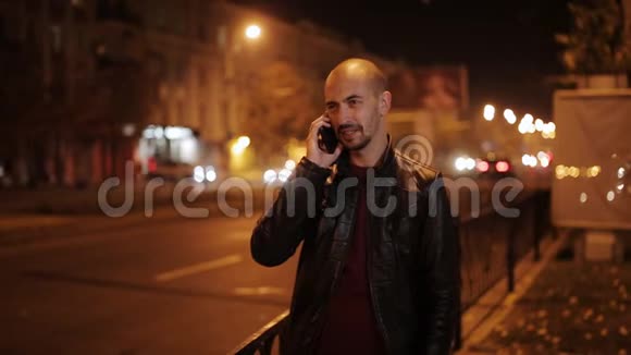 城市的智能手机人在晚上打手机英俊的年轻商人在智能手机上微笑视频的预览图