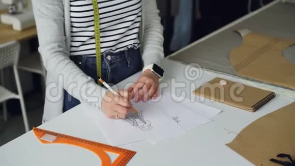 创意服装设计师的倾斜镜头集中在用一张纸绘制女性服装的草图上视频的预览图