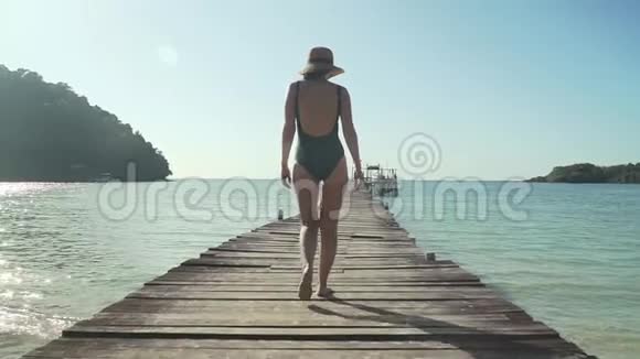 女人在热带海滩的木制码头上散步视频的预览图