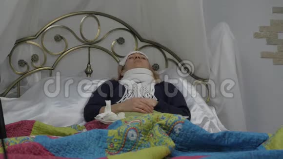 生病的女人躺在床上脖子上戴着一条温暖的围巾男人带着药丸和体温计4K视频的预览图
