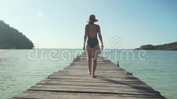女人在热带海滩的木制码头上散步视频的预览图