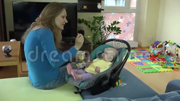 年轻的母亲用勺子喂她的宝贝女儿4K视频的预览图