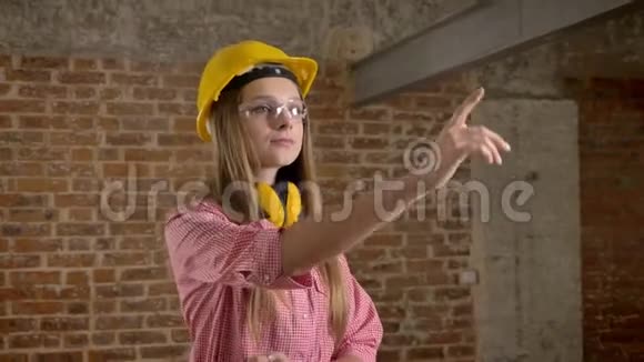 年轻自信的女建筑工指着上面的东西砖背景视频的预览图