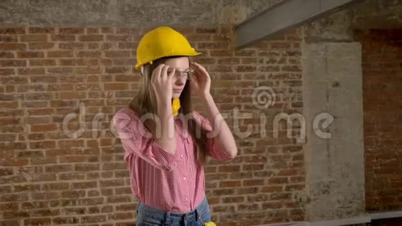 年轻苗条的女建筑工人戴着闪闪发光的眼镜双手交叉着身体自信地看着镜头看着砖头视频的预览图