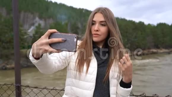女孩正在一条山河和森林的背景下自拍视频的预览图
