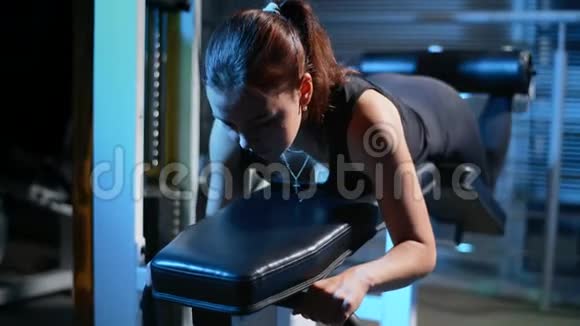 躺在模拟器里的女孩对大腿后部的肌肉进行锻炼二头肌臀部运动型妇女视频的预览图