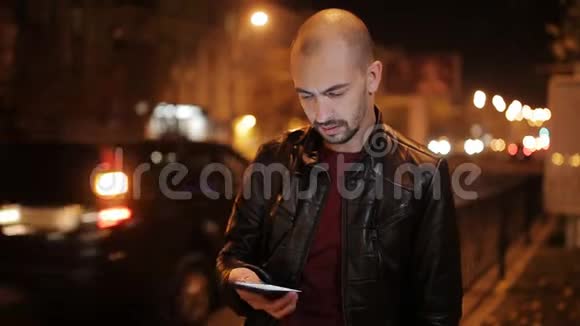 城市的智能手机人在晚上打手机英俊的年轻商人在智能手机上微笑视频的预览图