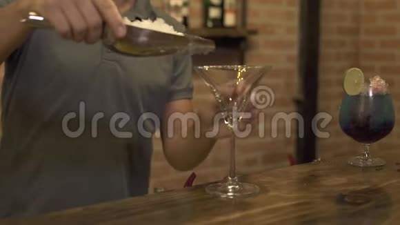 酒保把碎冰放在玻璃杯里在餐厅的吧台上做鸡尾酒酒保准备酒视频的预览图