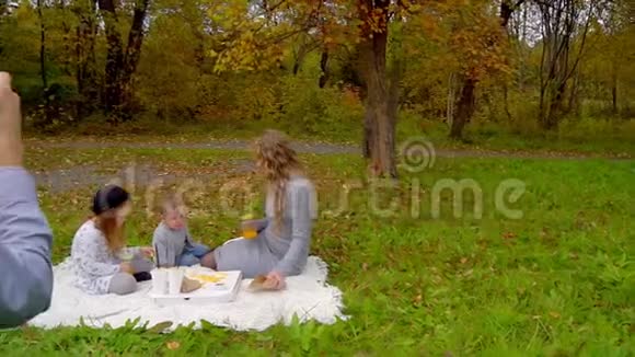 秋天在公园里野餐爸爸给他的妻子和孩子拍照视频的预览图