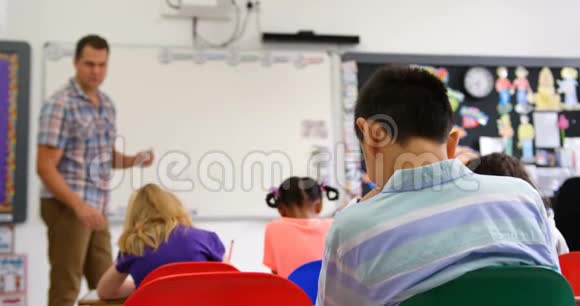 高加索男教师在4k教室白板上教学童的侧视图视频的预览图