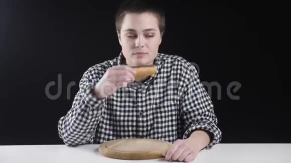 年轻的不平凡的女孩正在吃麦片用奶油弄脏饮食观念黑色背景视频的预览图