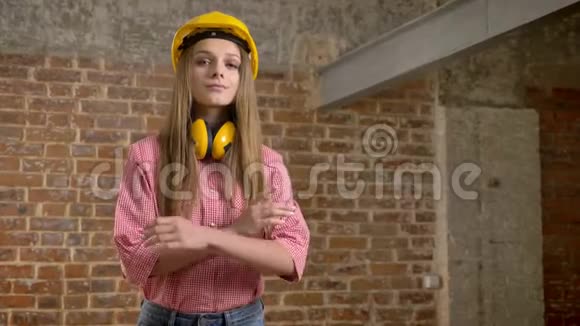 年轻自信的女建筑工人正交叉双臂扬眉点头看着镜头砖背景视频的预览图