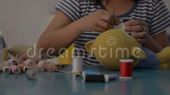 女人在家里的桌子上缝制和固定泰迪熊娃娃视频的预览图