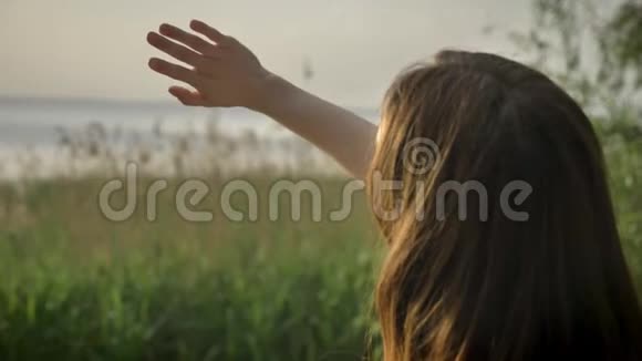 年轻快乐的女孩站在海边双手合拢阳光眩光阳光剪影50英尺视频的预览图