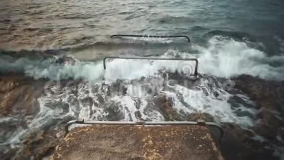 岩石海滩上的海浪白浪拍打在岩石海岸上视频的预览图