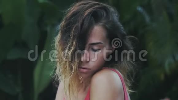 一位留着短卷发的漂亮模特喜欢在热带丛林中放松她的头发是棕色的视频的预览图