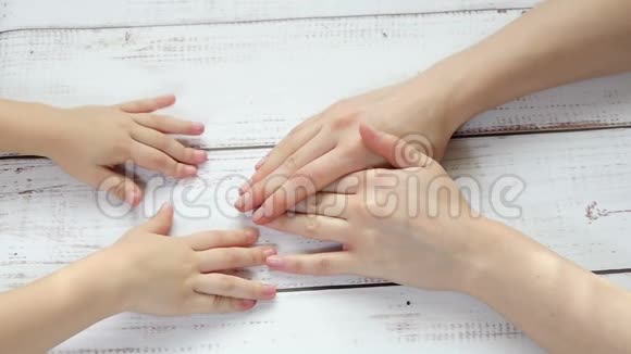 孩子的手触摸妈妈的手特写手牵手在木桌的背景下在一个视频的预览图