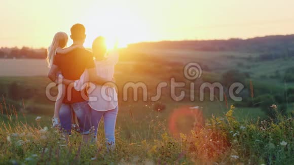 一个友好的家庭花时间在大自然中拥抱和享受日落视频的预览图