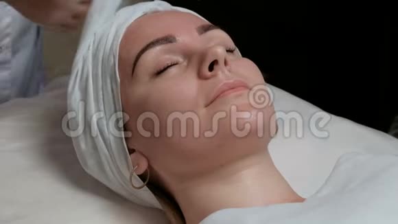 一个美丽的欧洲女孩在美容院的面部护肤程序一个带白色的化妆师视频的预览图