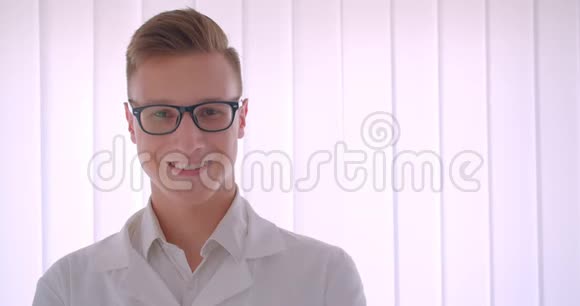 年轻英俊的白种人商人戴着眼镜看着镜头开心地站在室内视频的预览图
