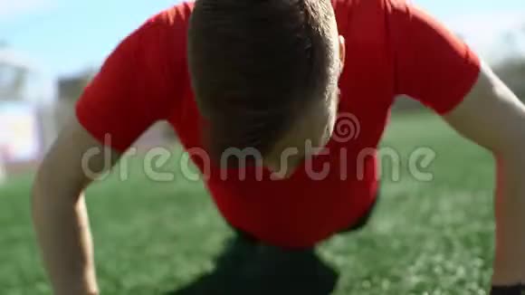 年轻的帅哥在球场草坪上做俯卧撑视频的预览图