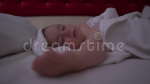 一个可爱的小男孩睡在大床上床上有白色的亚麻布动作缓慢视频的预览图