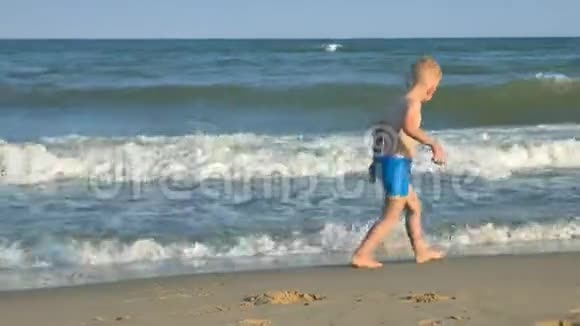 一个无家可归的小男孩沿着海边的海滩散步视频的预览图