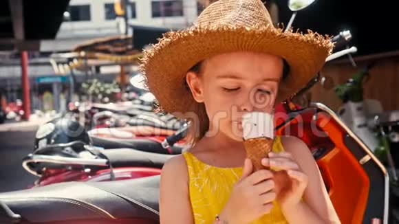 戴草帽的小女孩在户外街吃冰淇淋夏季肖像画视频的预览图