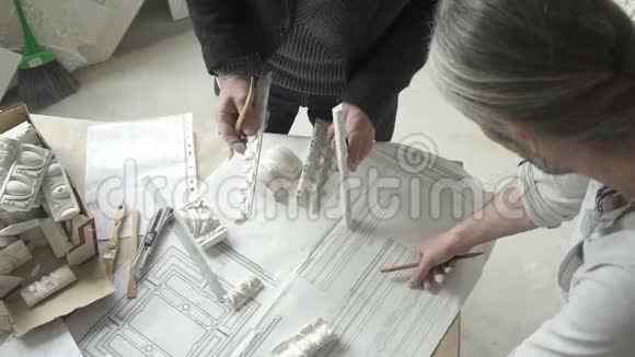主修复师在灯光车间的桌子上使用蓝图和石膏装饰视频的预览图