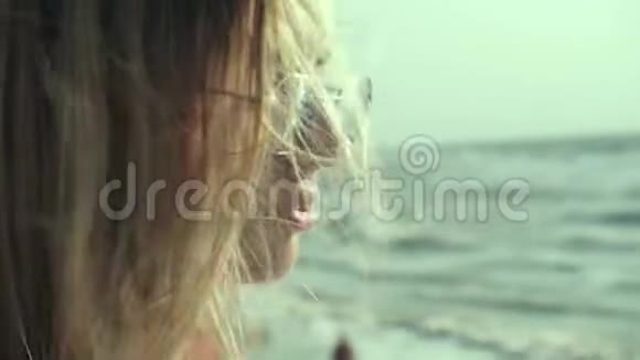 一个美丽的女孩的长发在风中在背景的海洋中生长视频的预览图