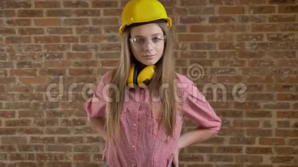 年轻自信的女建筑工人站在她的臀部看镜头砖背景视频的预览图