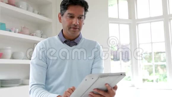 家庭厨房中使用数码平板的印度男人视频的预览图