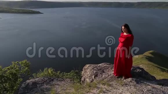 美丽的白种人女人穿着红色的裙子在河岸边为相机摆姿势视频的预览图