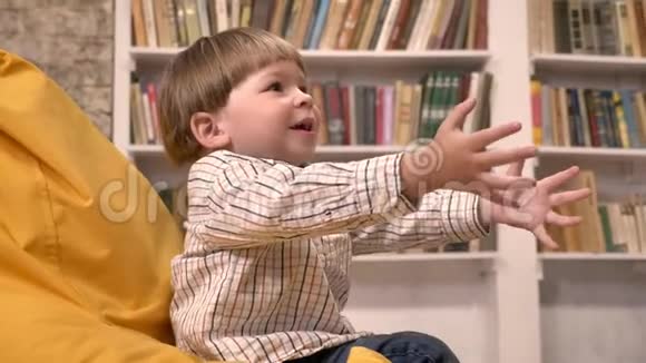 小男孩坐在椅子上接球和投掷球书架背景视频的预览图