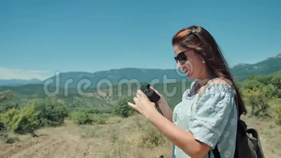 年轻的旅行者女士用室外相机拍摄令人惊叹的风景视频的预览图